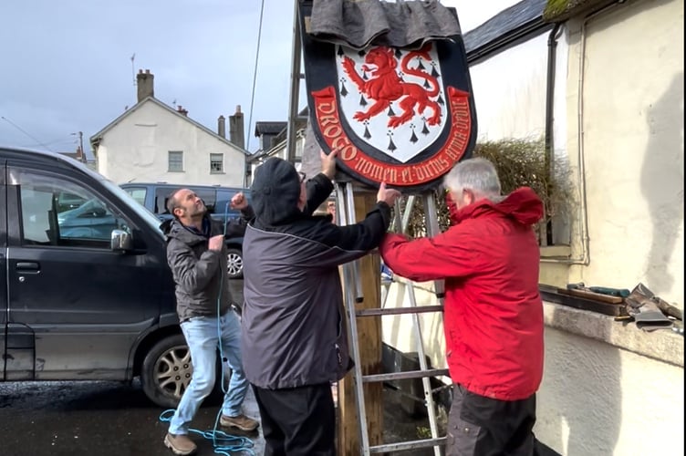 The Drewe Arms sign being raised and put back into pride of place.
