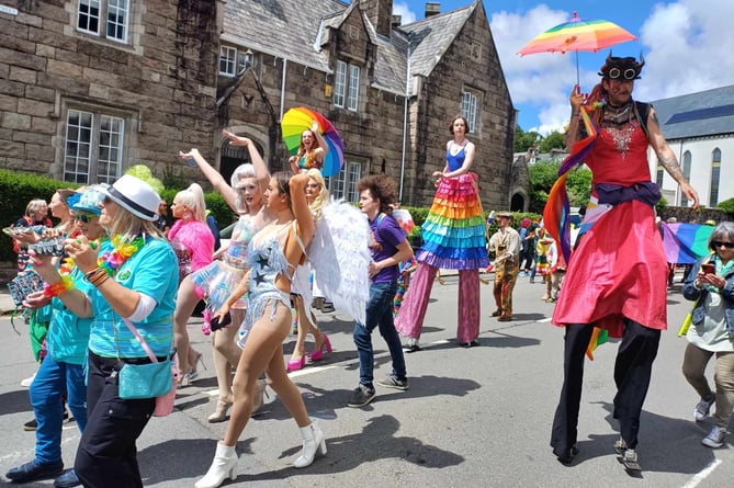 Tavi Pride procession with stilt walkers and some well-turned out marchers.