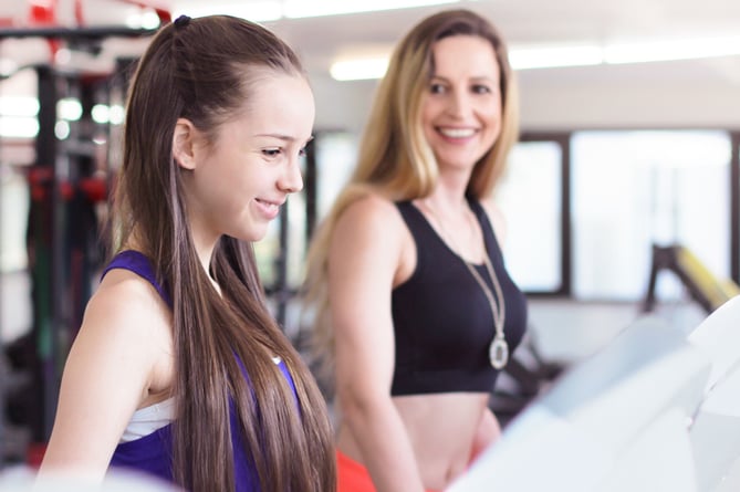 Mother and daughter training. Beautiful mature woman and her teenage daughter in the gym