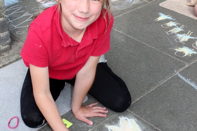 A young creative girl shows off her chalk skills with some pavement designs in Tavistock for the town's carnival week