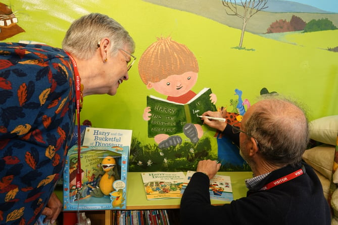 Artist Anne Crozier watches as author Ian Whybrow signs his name on her handiwork - his book The Bucketful of Dinosaurs