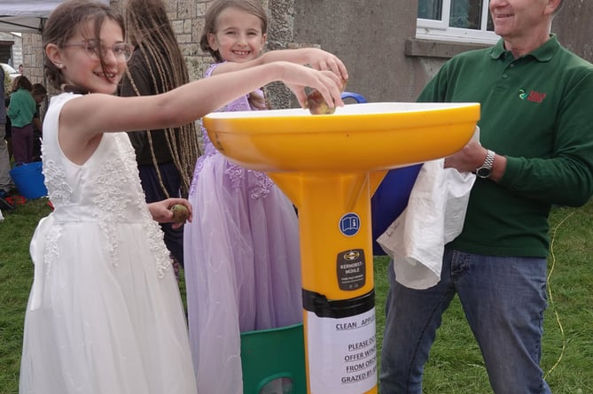 Carnival queen and attendant Ruby and Amber Parkin feed the apple crusher