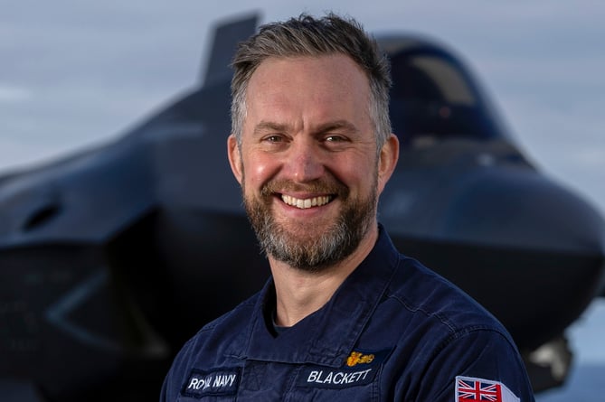 Captain Will Blackett in front of an F-35 on the flight deck of HMS Prince of Wales